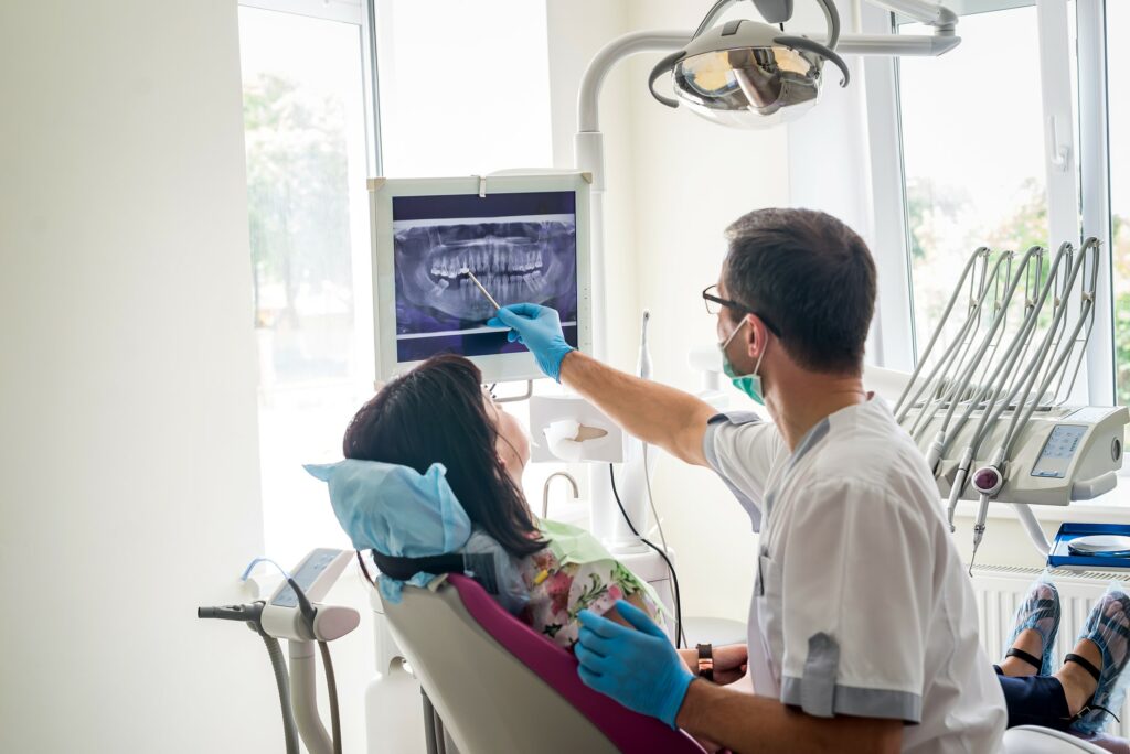 Dental professional having a chair-side conversation and showing an X-ray to a patient.