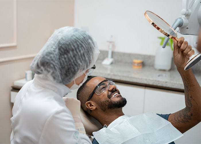 Patient smiling into a mirror while a dental professional sits chair-side.