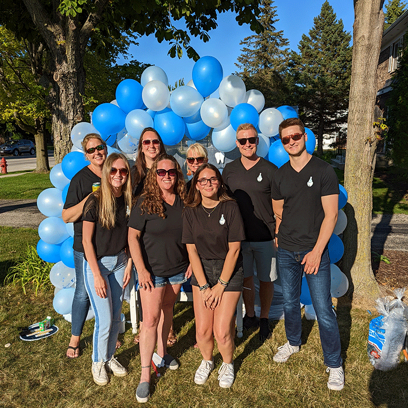 Group photo of the Port Washington Family Dentistry staff outside in front of a balloon arch.
